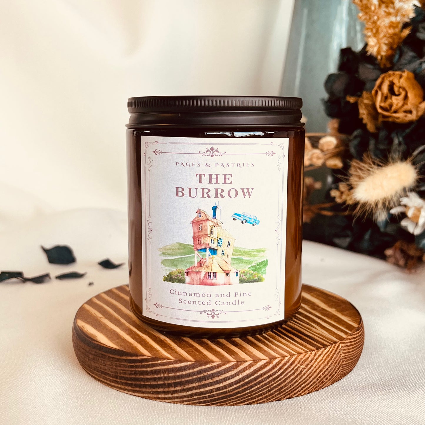 The Burrow bookish candle in amber glass jar with black lid, showing Weasley home and flying car label design