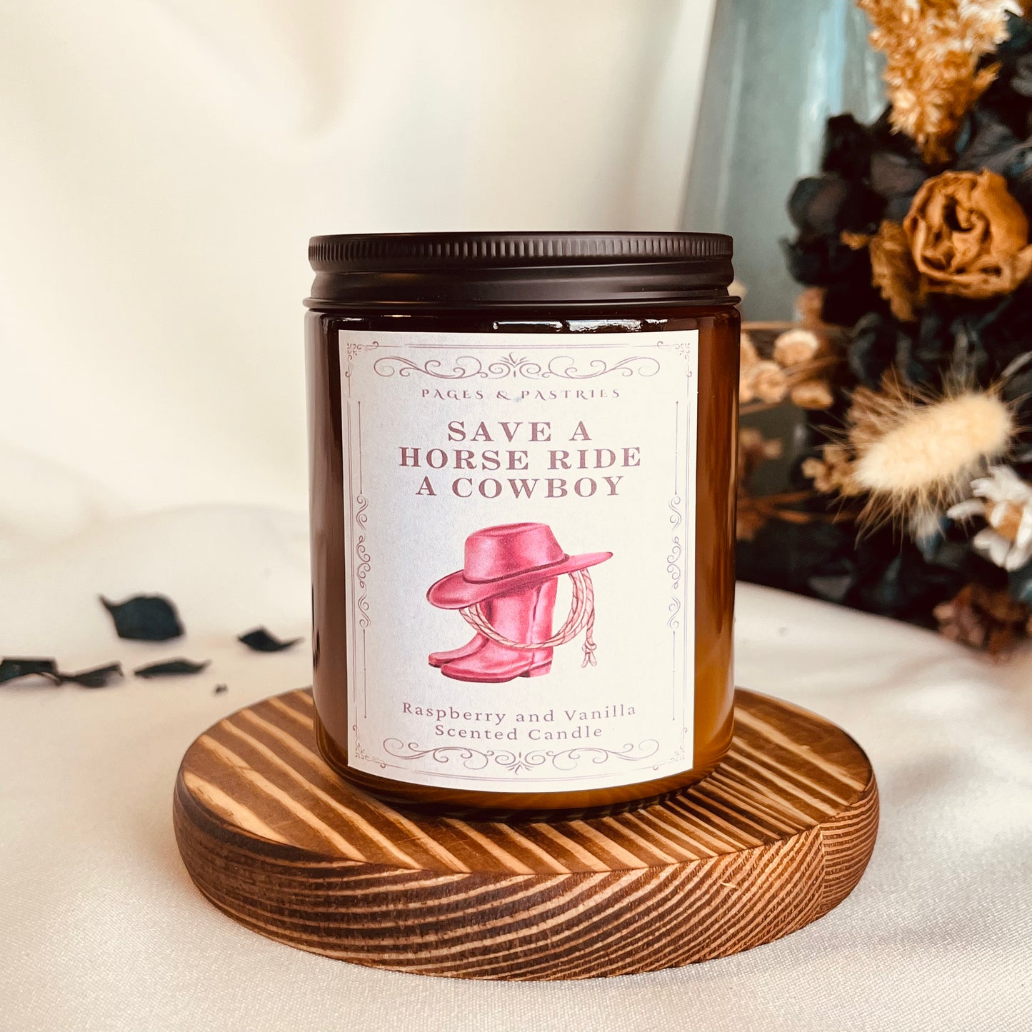 Cowboy Romance bookish candle in amber glass jar with black lid, showing pink cowgirl boots and hat label design