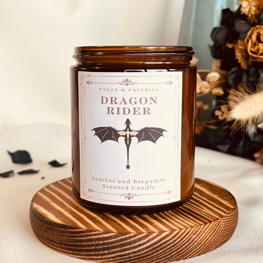 Dragon Rider bookish candle in amber glass jar with black lid, showing dragon design on label