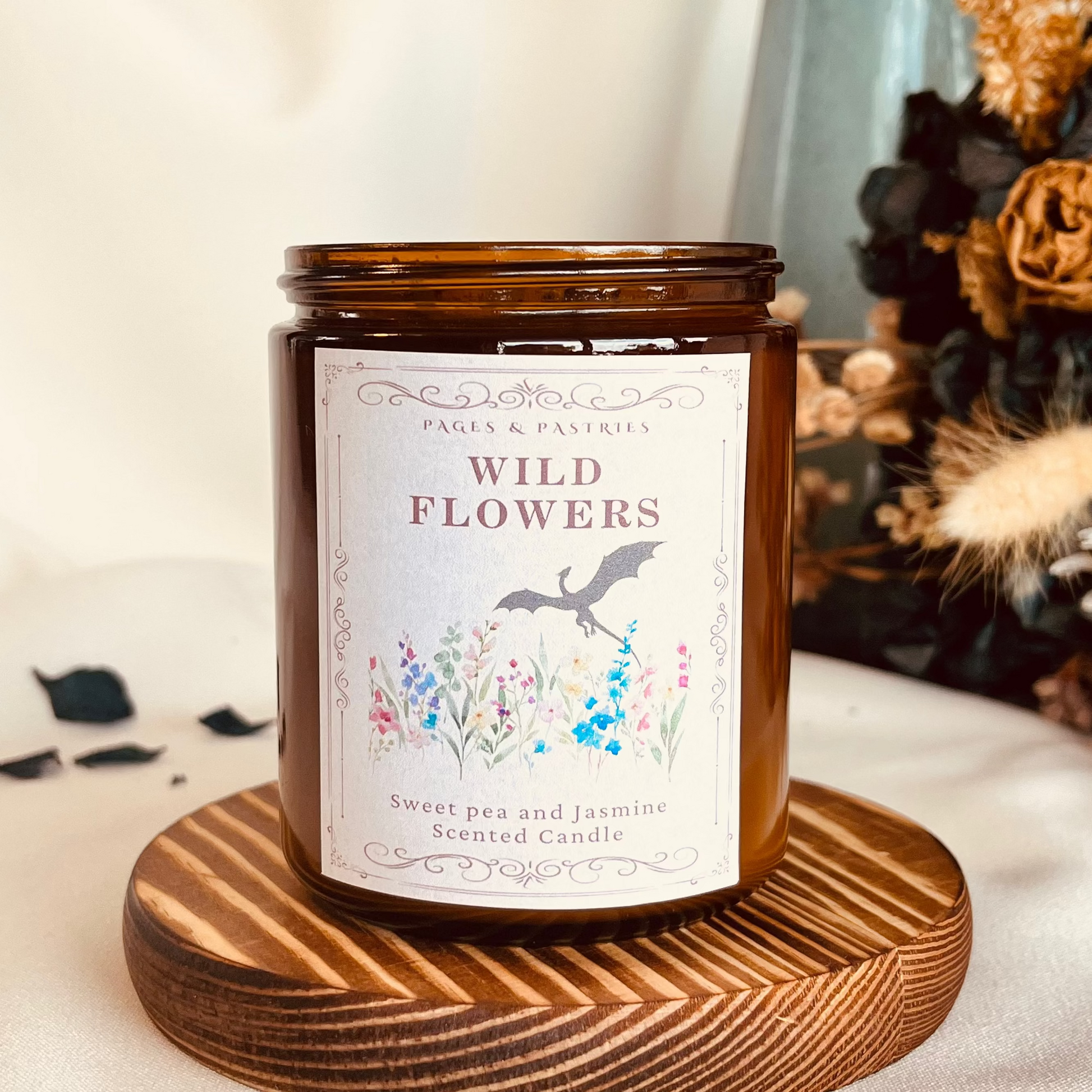 Wild Flowers bookish candle in amber glass jar, sweet pea and jasmine scented, showing wyvern among wildflowers on label