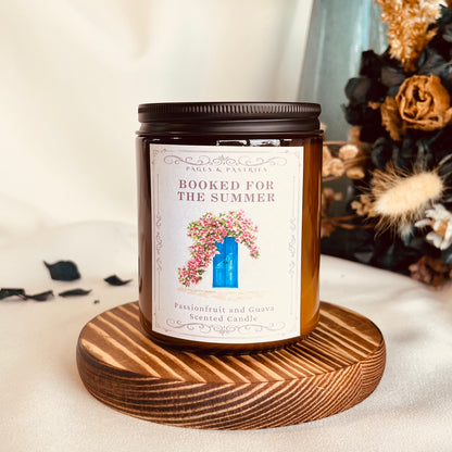 Booked for the Summer bookish candle in amber glass jar with black lid, showing Greek door and flowers label design